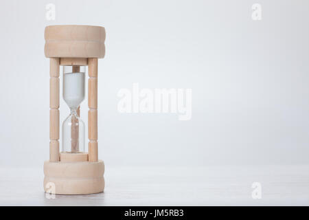 Small wooden egg timer or hourglass with sand running through the bulbs in a concept of measurement of passing time, deadlines or cooking with copy sp
