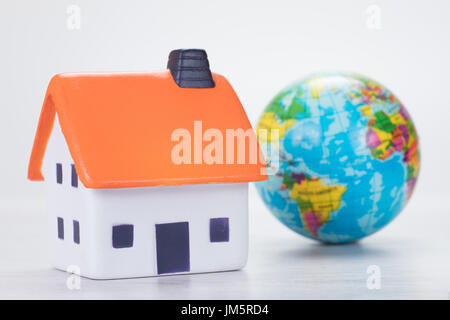 Model house with a world globe alongside in a conceptual image of saving the planet through eco-friendly construction and use of resources Stock Photo