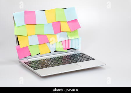 Business multitasking, ideas and organisation concept with colorful sticky notes completely covering an open laptop screen over a white background Stock Photo