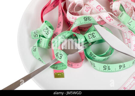 Tape measures and fork on a plate in a healthy eating dieting and weight loss concept in a close up high angle view Stock Photo