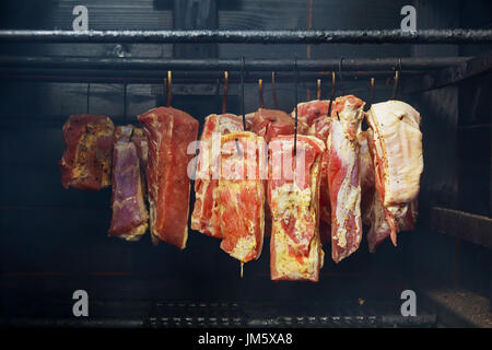 Hanging ham in the smokehouse smoked bacon for smoking Stock Photo