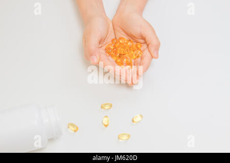 Fish oil omega 3 capsules in hands over white background Stock Photo