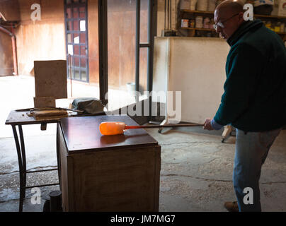 The glassblowers work in their workshop on Murano island, Venice, Italy Stock Photo