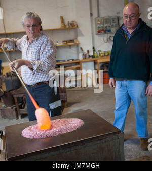 The glassblowers work in their workshop on Murano island, Venice, Italy Stock Photo