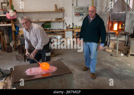 The glassblowers work in their workshop on Murano island, Venice, Italy Stock Photo