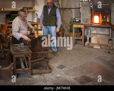 The glassblowers work in their workshop on Murano island, Venice, Italy Stock Photo