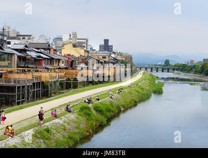 KYOTO, JAPAN - July 24, 2017: As afternoon turns to evening, couples sit on the banks of the Kamo River in Kyoto, Japan