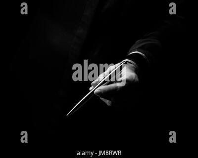 Black Mania. female hand isolated on black giving a pen Stock Photo