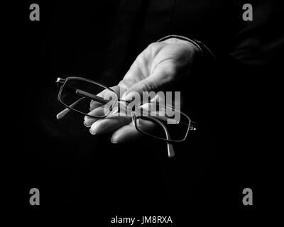 Black Mania. female hand isolated on black showing spectacles Stock Photo