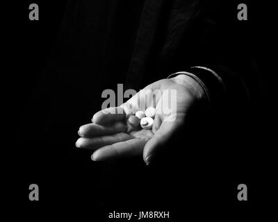 Black Mania. woman hand isolated on black showing pills Stock Photo