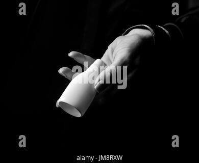 Black Mania. woman hand isolated on black showing bottle of medical drops Stock Photo