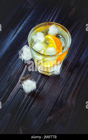 Cold cocktail with orange, tonic, vodka and ice on wood dark background Stock Photo