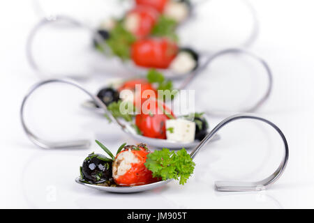 Stuffed hot cherry peppers, black olives and feta cheese on decorative appetizer spoons Stock Photo