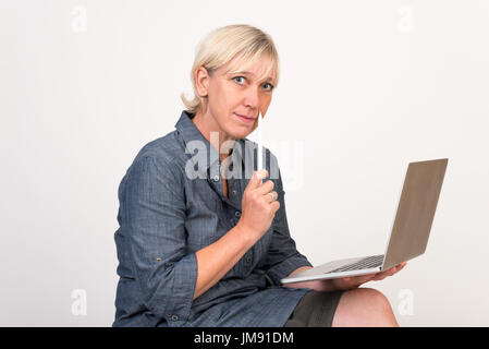 beautiful european mid aged woman working at a laptop thoughtful Stock Photo