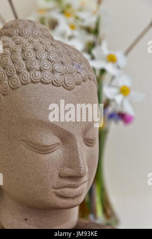 Buddha statue surrounded by vibrant color flowers Stock Photo