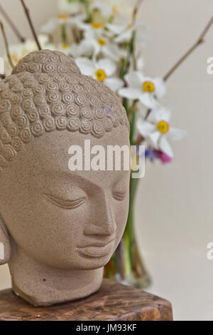 Buddha statue surrounded by vibrant color flowers Stock Photo