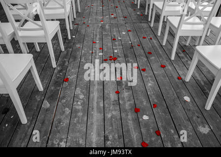 Wedding white chairs aisle with the red rose petals on the wooden floor Stock Photo