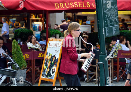 Brussels, Belgium. Young female busker playing the melodica in central Brussels Stock Photo