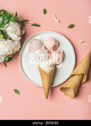 Pink strawberry and coconut ice cream, cones and white peonies Stock Photo