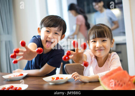 Happy Chinese siblings and cherry tomatoes Stock Photo