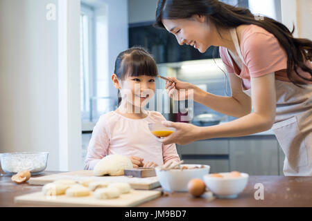 Happy young Chinese mother and daughter baking together Stock Photo