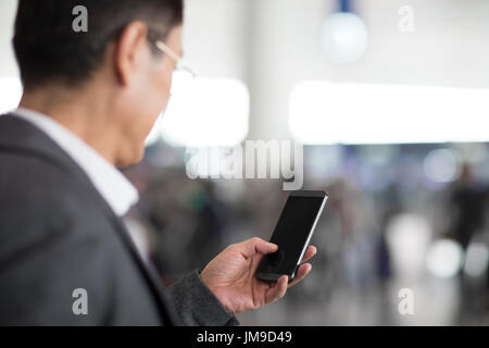 Chinese businessman using smart phone in airport Stock Photo