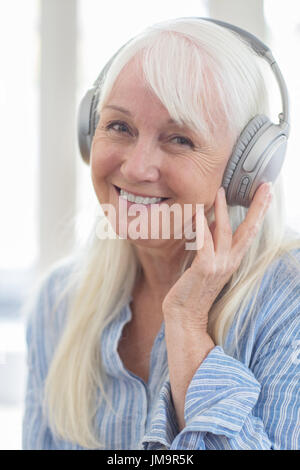 Senior Woman Listening To Music On Wireless Headphones Stock Photo