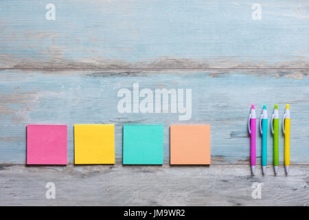 Retro blue wooden table with empty colorful sticky notes and different color pens Stock Photo