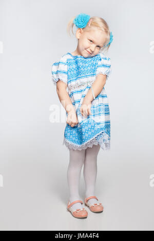 Cute little blonde girl on a white background shy Stock Photo