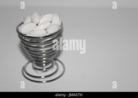 White pills in spiralled egg cup Stock Photo