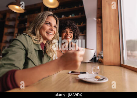 Two young woman sitting at cafe and having coffee. Female friends drinking coffee at restaurant. Stock Photo