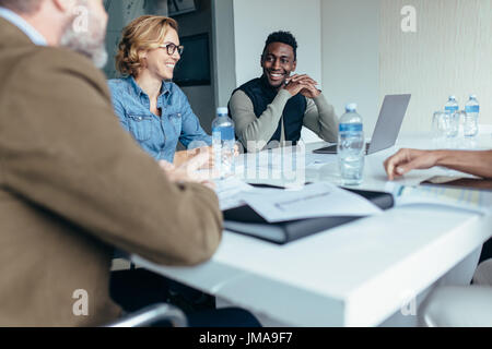 Smiling businesswoman in meeting with colleagues in conference room. Female manager leads brainstorming meeting in design office. Stock Photo
