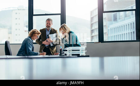 Business team working together in office. Team of three businesspeople discussing building plans in meeting. Stock Photo