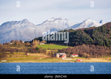 Agricultural and mountain scenery on the island of Handnesøya ear the village of Nesna, Nordland County, Norway.  Seen from a Hurtigruten cruise ship. Stock Photo