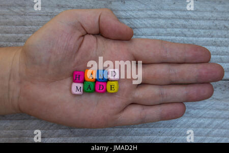 Handmade letter cube in hand on gray wood visualization. Stock Photo