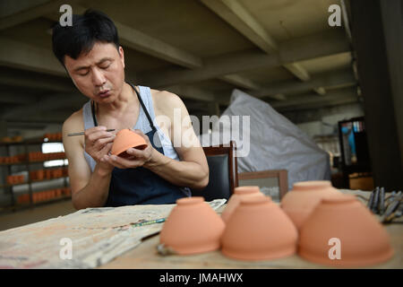 (170726) -- JIANYANG, July 26, 2017 (Xinhua) -- Lu Jinxi, a jian ware porcelain craftsman, works on a porcelain bowl in a workshop in Jianyang District of Nanping City, southeast China's Fujian Province, July 25, 2017. The jian ware porcelain, flourished in Song Dynasty (960-1279), famous for its golden black glaze with streaks of 'hare's fur', is revived in recent decades after 600 years of disappearance of the knowhow of its manufacture. Lu Jinxi, 45, is one of the first craftsmen who rediscovered the long-lost art of the making of the heritage crafts.  (Xinhua/Song Weiwei) (clq)(zt) Stock Photo