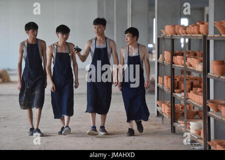 (170726) -- JIANYANG, July 26, 2017 (Xinhua) -- Lu Jinxi(2nd R), a jian ware porcelain craftsman, talks with young learners in a workshop in Jianyang District of Nanping City, southeast China's Fujian Province, July 25, 2017. The jian ware porcelain, flourished in Song Dynasty (960-1279), famous for its golden black glaze with streaks of 'hare's fur', is revived in recent decades after 600 years of disappearance of the knowhow of its manufacture. Lu Jinxi, 45, is one of the first craftsmen who rediscovered the long-lost art of the making of the heritage crafts.  (Xinhua/Song Weiwei) (clq)(zt) Stock Photo