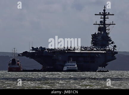 Portsmouth, England. 27th July, 2017. - US Carrier Visit - The USS George H W Bush, an American Nimitz class aircraft carrier and one of the largest of its type in the world, arrived in the Solent today to embark Royal Navy personnel. The carrier, seen here anchored in Stokes Bay, is scheduled to start the final part of Operation Inherent Resolve, a two week training exercise for Global Coalition forces against ISIS. Two Type 23 frigates HMS Iron Duke and Westminster with RFA Wave Ruler will join the exercise.  Photo: Steve Foulkes/Ajax/Alamy Live News. Stock Photo