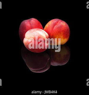 Three ripe nectarines on a black background isolated with real reflection