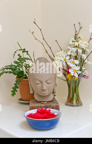 Buddha statue surrounded by vibrant color flowers Stock Photo