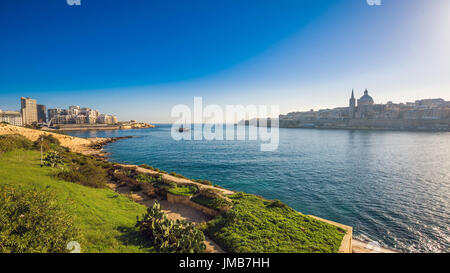 Valletta, Malta - Skyline view of the ancient city of Valletta and Sliema at sunrise shot from Manoel island at spring time with sailing boat, St.Paul Stock Photo