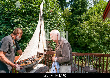 Elderly Father and Adult Son Working Together on a Model Sailboat Stock Photo