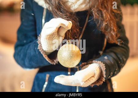 Female hands holding a Christmas gold ball. Frosty winter day in snowy forest. Merry Christmas and Happy New Year theme Stock Photo
