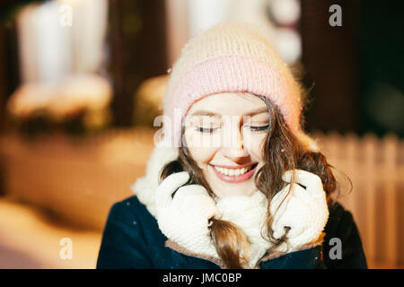 Happy winter time in big city of charming girl walking on street in coat with backpack. Enjoying snowfall, expressing positivity, smiling to camera, j Stock Photo