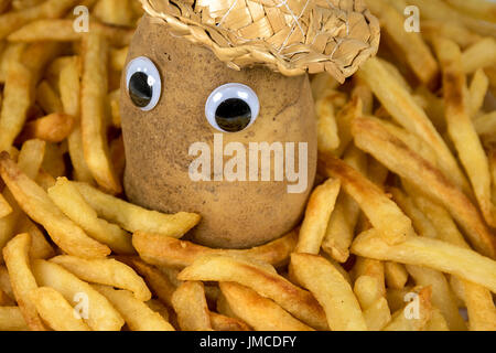 raw potato with straw hat and eyeballs in a pile of golden french fries Stock Photo