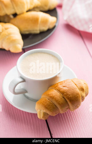 Sweet tasty croissants and coffee cup on pink table. Stock Photo