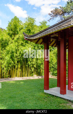 A red wooden buddhist temple with a bamboo grove in the background. Stock Photo