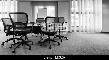 Ergonomic office chairs around a table. Empty conference room. Vertical window blinds. Black and white Stock Photo