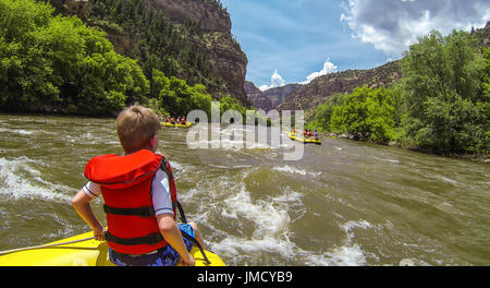 A young boy or man rides the bull during a White Water River Rafting Expedition on the Colorado River in Glenwood Canyon near Glenwood Springs Stock Photo