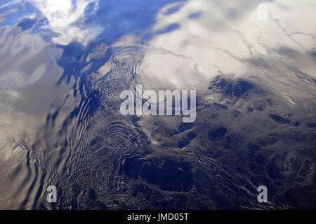Smooth ocean surface reflecting clouds and sky with ripples Stock Photo